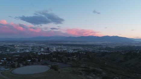 Fy-over-shot-revealing-downtown-Salt-Lake-City,-Utah-with-tall-building-and-pink-clouds-in-the-background