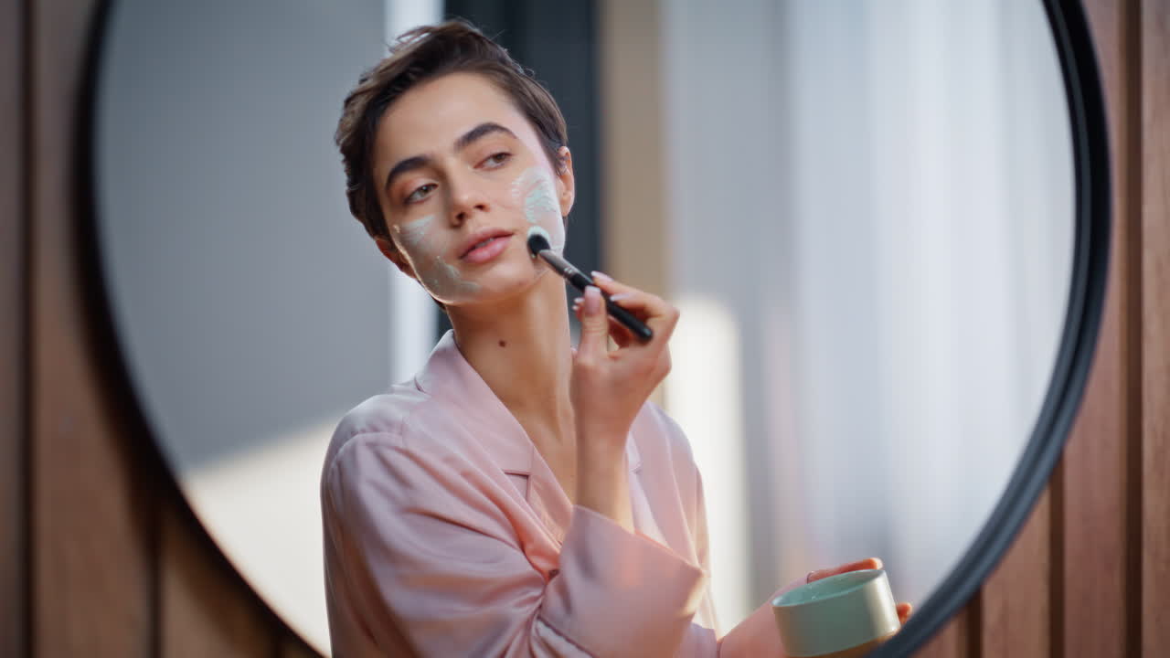 Face mask woman beauty routine home closeup. Relaxed groomed lady looking mirror