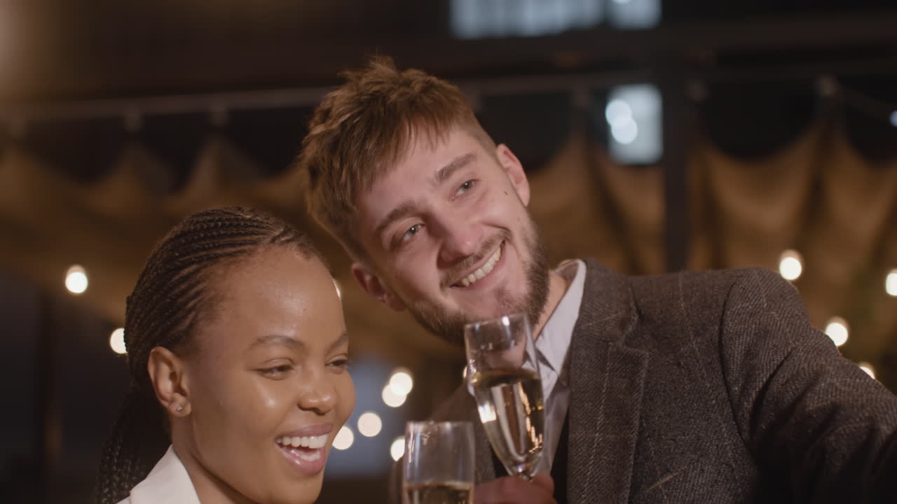 Ritratto di un Uomo e una Donna che brindano con calici di champagne mentre si riprendono in un video selfie alla festa di Capodanno