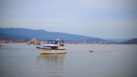 Boat-passing-slowly-in-Vancouver-Downtown-Coal-Harbour,-pulling-another-smaller-boat