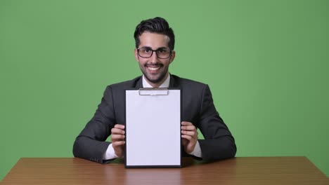 young handsome bearded persian businessman against green background
