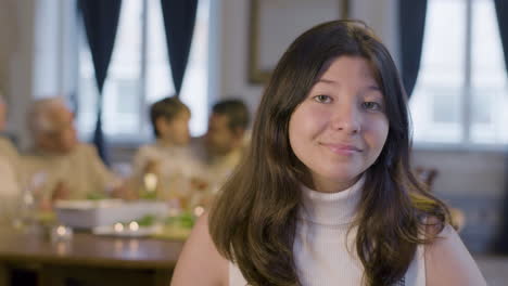 portrait of a pretty teenage girl looking at camera and smiling while spending time with her family during a party at home