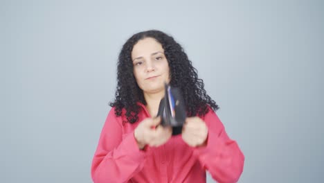 una joven sin dinero mirando su billetera vacía.