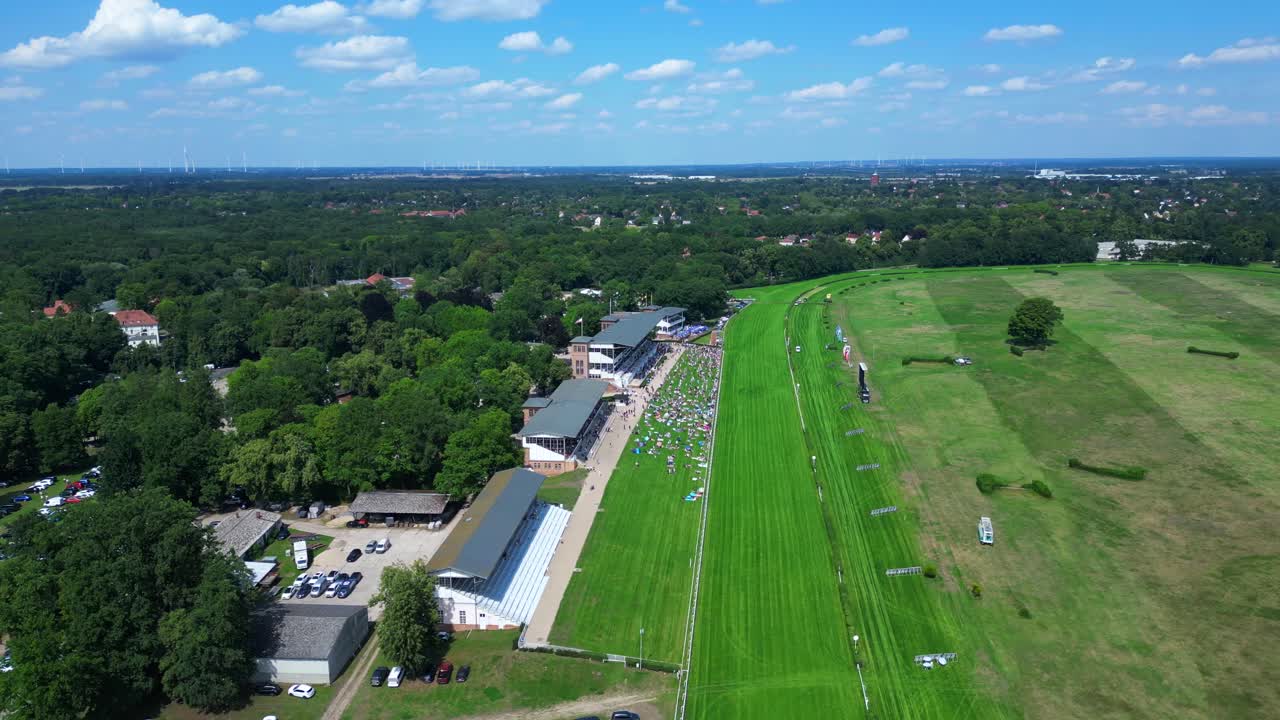 horse racing track with spectators enjoying the competition on a sunny summer day. Dramatic aerial view flight panorama orbit drone