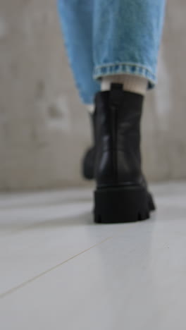 model wearing jeans and white socks demonstrates black boots. convenient cold weather footwear for females close up. vertical video