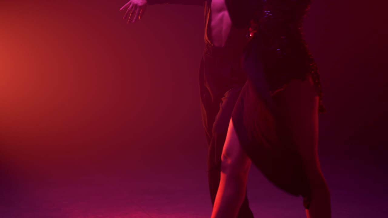 el cuerpo de los bailarines se mueve en el fondo oscuro. una pareja desconocida bailando rumba en el interior.