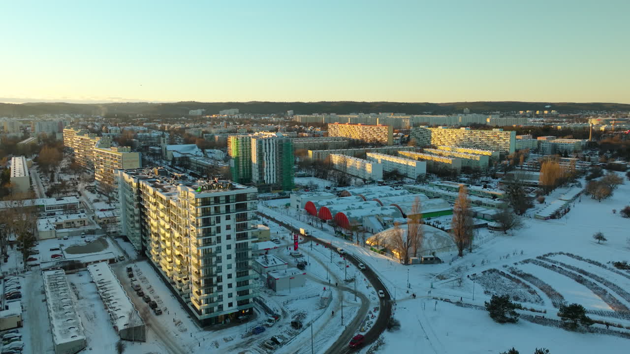 Etablerende droneoptagelse fra luften af et polsk blokkvarter med biler på vejen på en snefuld vinterdag ved solnedgang i Gdansk.