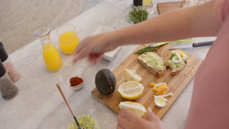 preparing healthy breakfast, woman spreading avocado on toast with boiled eggs