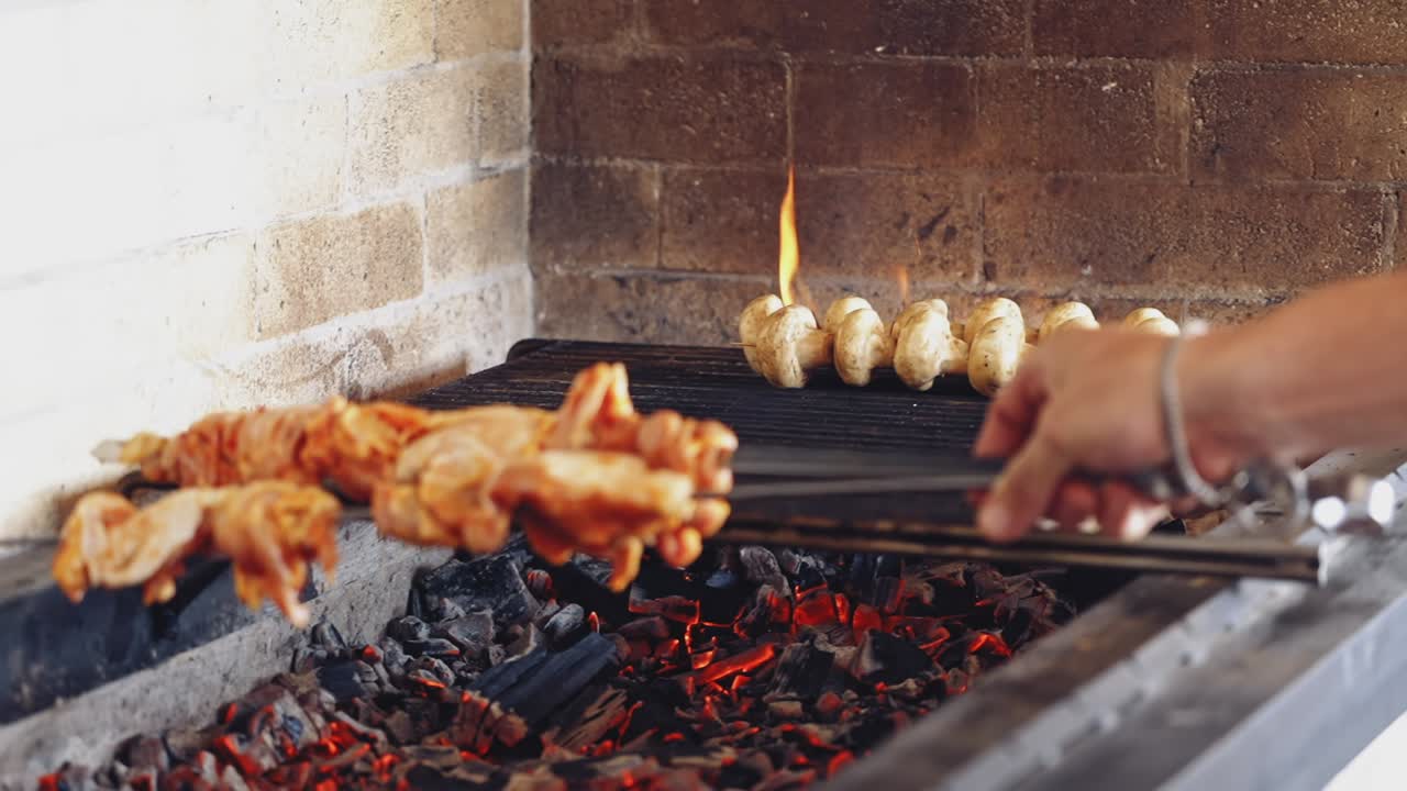 Cooking mushrooms on grill. Cook puts some skewers with chicken meat on charcoal. Preparing the barbeque on the restaurant kitchen.