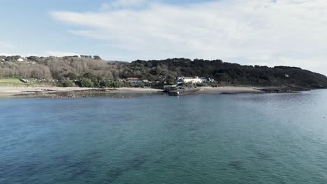 aproximación baja sobre el mar a la isla de herm, las islas del canal sobre el mar tranquilo a la playa y el muelle con el hotel whitehouse