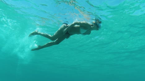 underwater shot of woman snorkeling in clear blue sea, view from below