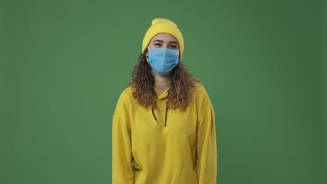 mujer con máscara protectora y riendo sobre la pantalla verde