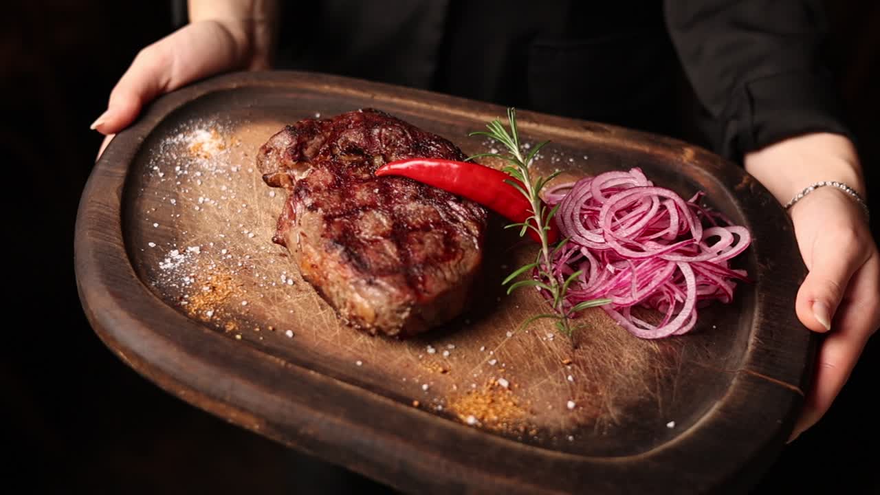 una mujer sirviendo un filete a la parrilla.