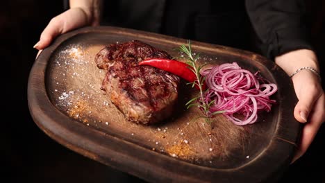 una mujer sirviendo un filete a la parrilla.
