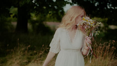 attractive boho woman walking on a meadow in summer holding flowers in hand 1