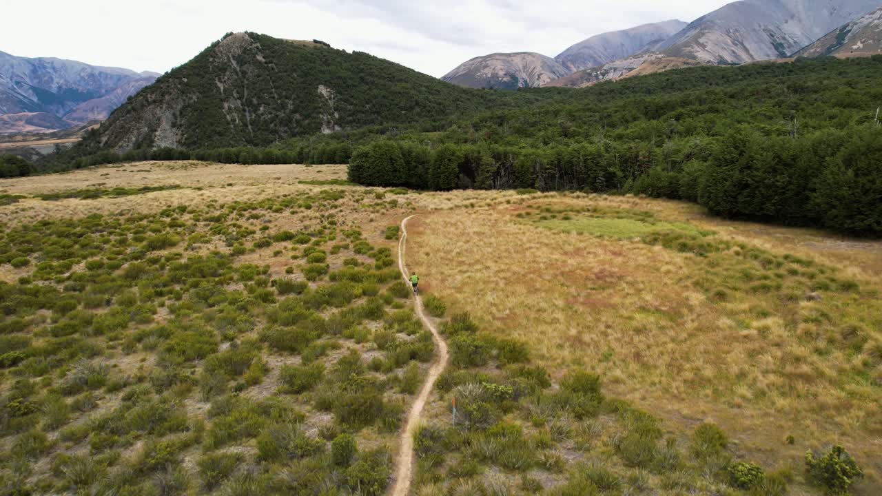 Aerial view following a person mountain biking in wilderness of Cragieburn, NZ