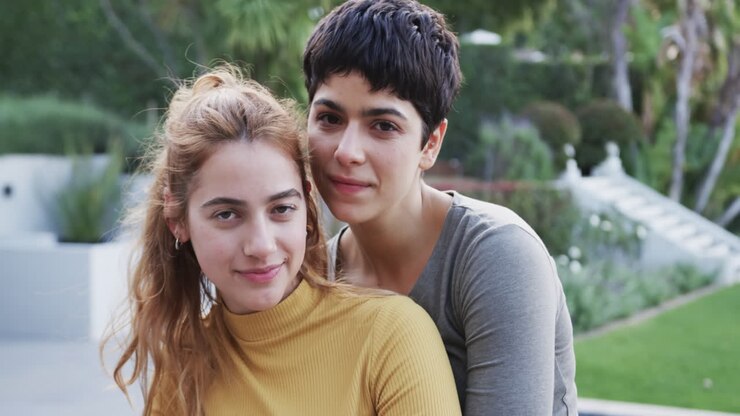 Happy caucasian lesbian couple embracing and smiling in front of house