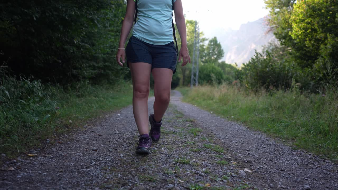 Mulher fazendo trilha em um caminho de cascalho na natureza