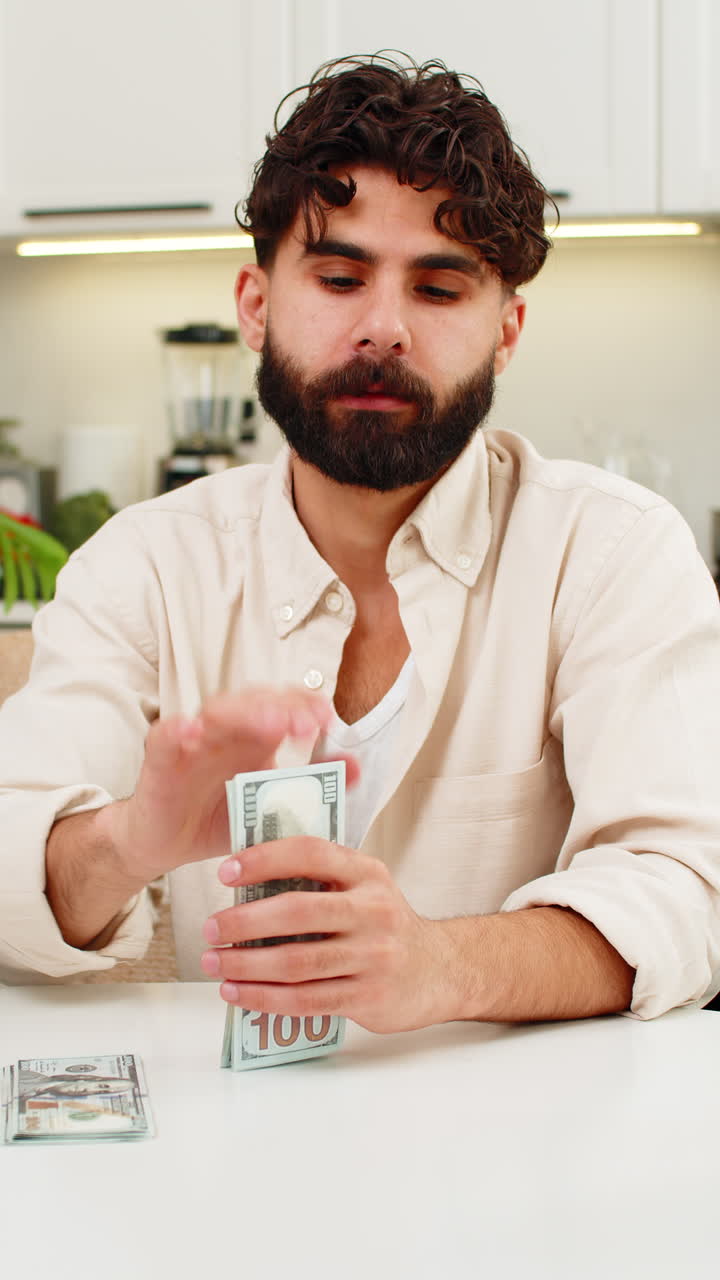 Hombre indio contando ahorros en dólares en pilas ordenadas, planificando su presupuesto y soñando con una futura compra.
