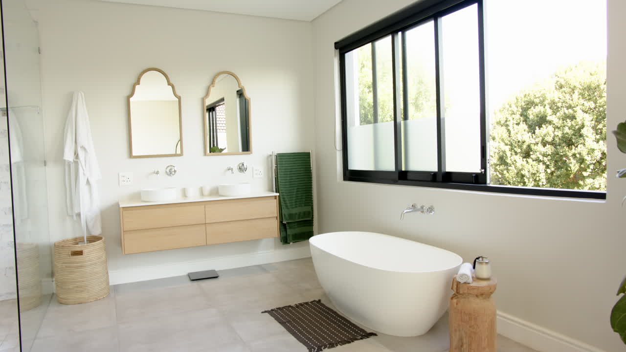 Modern bathroom with freestanding bathtub, double sink vanity, and large window, copy space