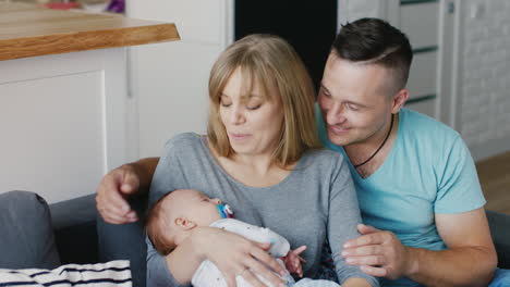young happy family with a baby in her arms relaxing at home smiling