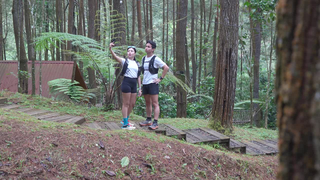 Asian couple taking photos during outdoor adventure in forest