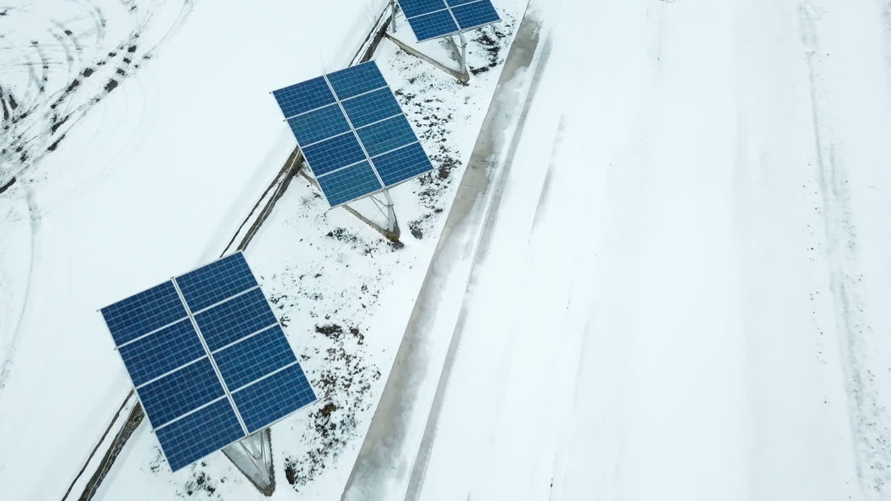 Aerial solar farm low flight in winter. Series of solar panels covered with snow.