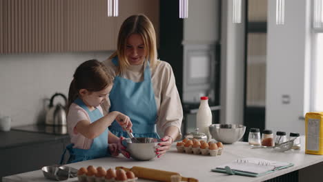 mother is teaching her daughter to cook in cozy kitchen of apartment in sunday morning