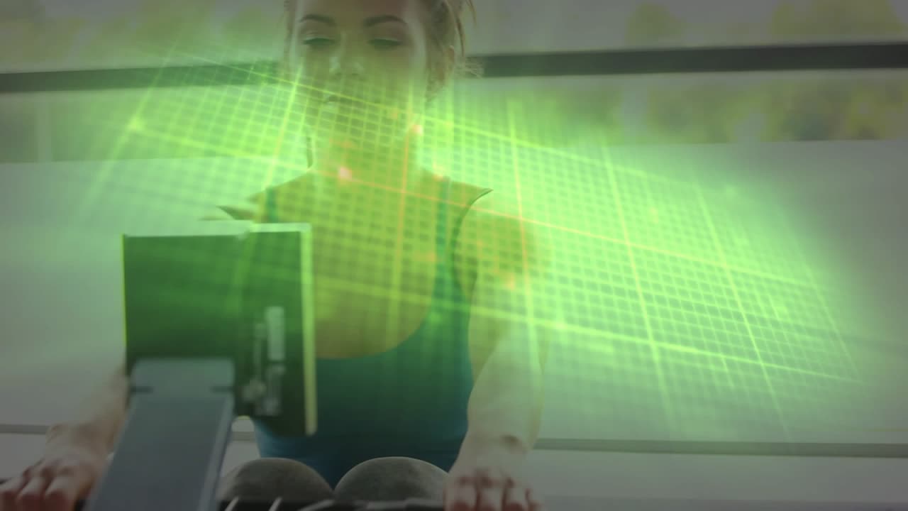 Woman on rower driving legs pulling handle and checking console, green overlay tracking fitness