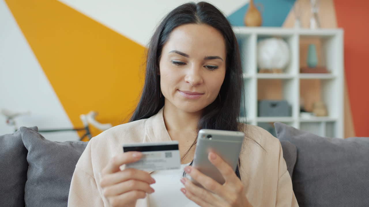 Woman using mobile phone and credit card for online shopping at home
