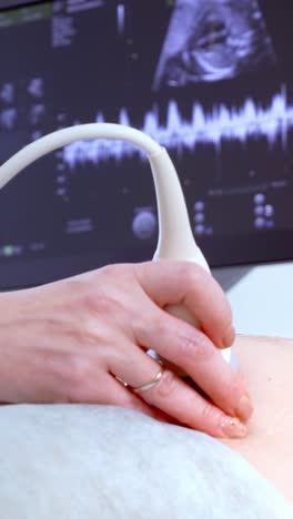 medical professional using ultrasound device on patient with monitor displaying results