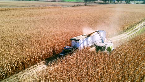 backwards flight over farm vehicles gathering corn during harvest season