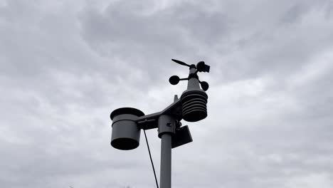 weather station against a cloudy sky in the day with a plane flying by