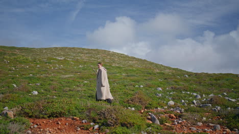 solo traveler going hill on sunny day. reflective woman hiking grassy mountain