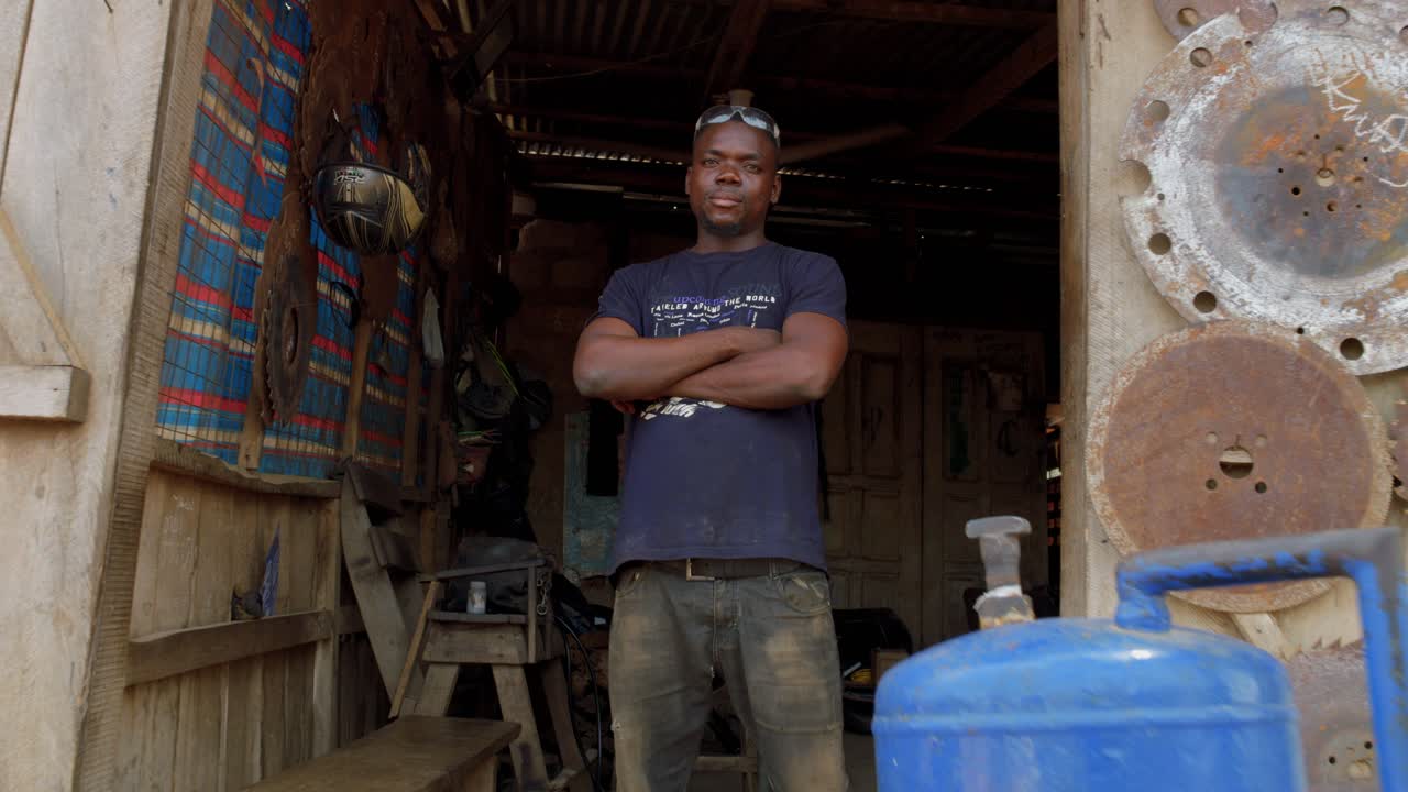 trabalhador afro-americano sorrindo para a câmera em sua loja de reparação de metal estúdio tiro largo