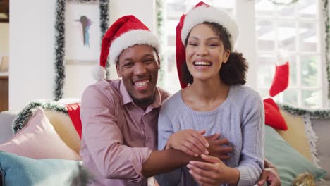 Portrait-of-happy-african-american-couple-with-santa-hats-having-video-call