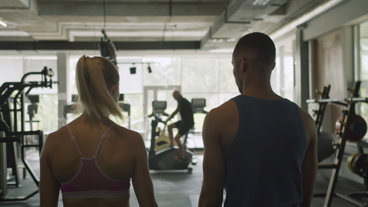 백인 여성 모니터와 체육관에서 운동하는 아프리카계 미국인 남자의 뒷면.