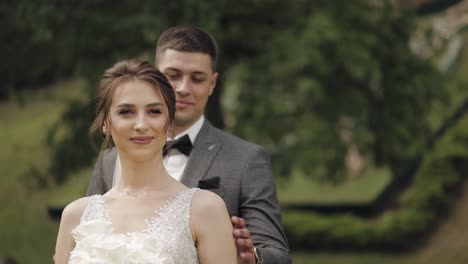 newlyweds, caucasian groom with bride walking, embracing, hugs in park, wedding couple