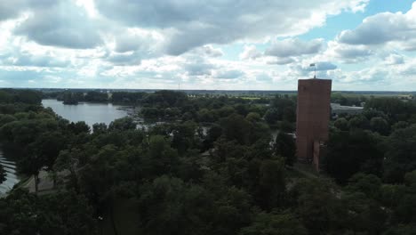 medieval-tower-near-lake-and-trees-on-cloudy-day-aerial-circulating