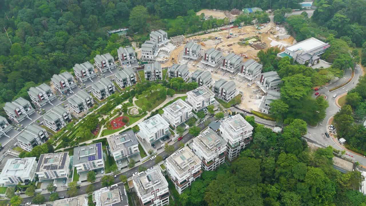 Aerial view of luxury housing development in Petaling Jaya, Kuala Lumpur, surrounded by greenery and ongoing construction in a forested suburban area. UHD.