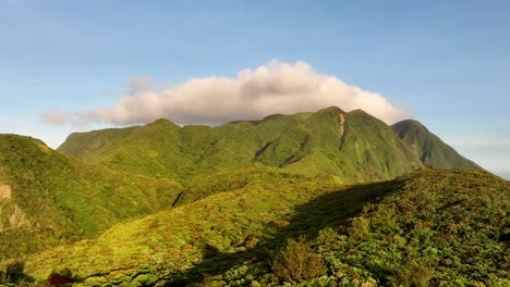 Aerial approaching shot of green covered mountains on Orchid Island 蘭嶼 during golden hour in Taiwan, Asia - White Clouds behind summit at blue sky