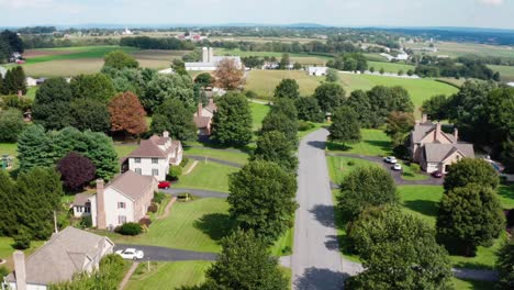 Aufsteigende-Antenne-Gehobener-Wohlhabender-Amerikanischer-Vororte-Zwischen-Ländlichen-Farmfeldern-Im-Sommer