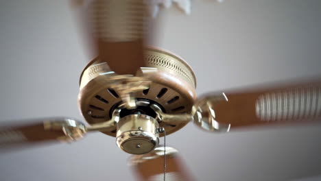 ceiling fan spinning, wooden and gold decorated, close up