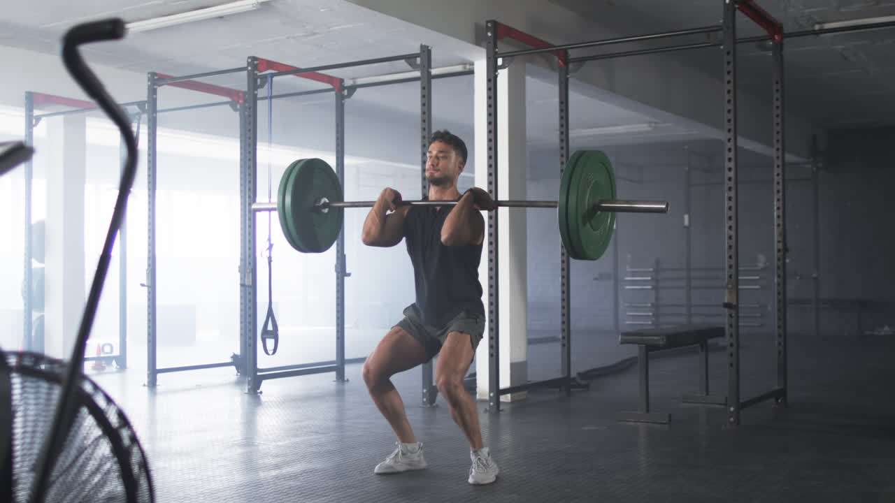 Lifting barbell, man working out in gym, focusing on strength training