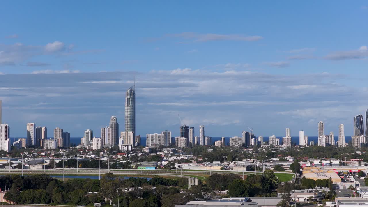 Aerial footage captures the Gold Coast skyline under clear blue skies, highlighting modern skyscrapers and coastal scenery in daylight