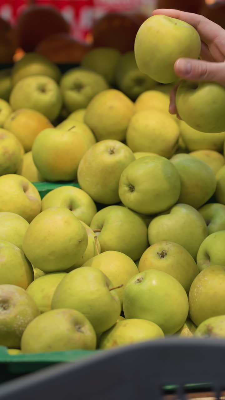 매장 안의 디스플레이에서 사과를 집어 들고 있는 손의 모습 - 손이 두 개의 사과를 선택하고 가져가는 모습 - 드 헬드 카메라로 촬영