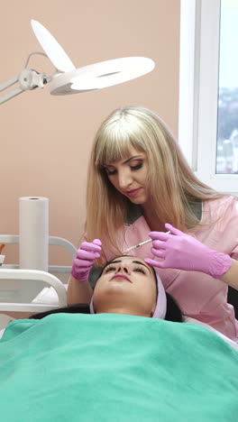 young pretty woman receiving treatments in beauty salons. young beautiful dark-haired woman in the office beautician lying on the couch. contouring procedure , revitalization. beauty injections . vertical video