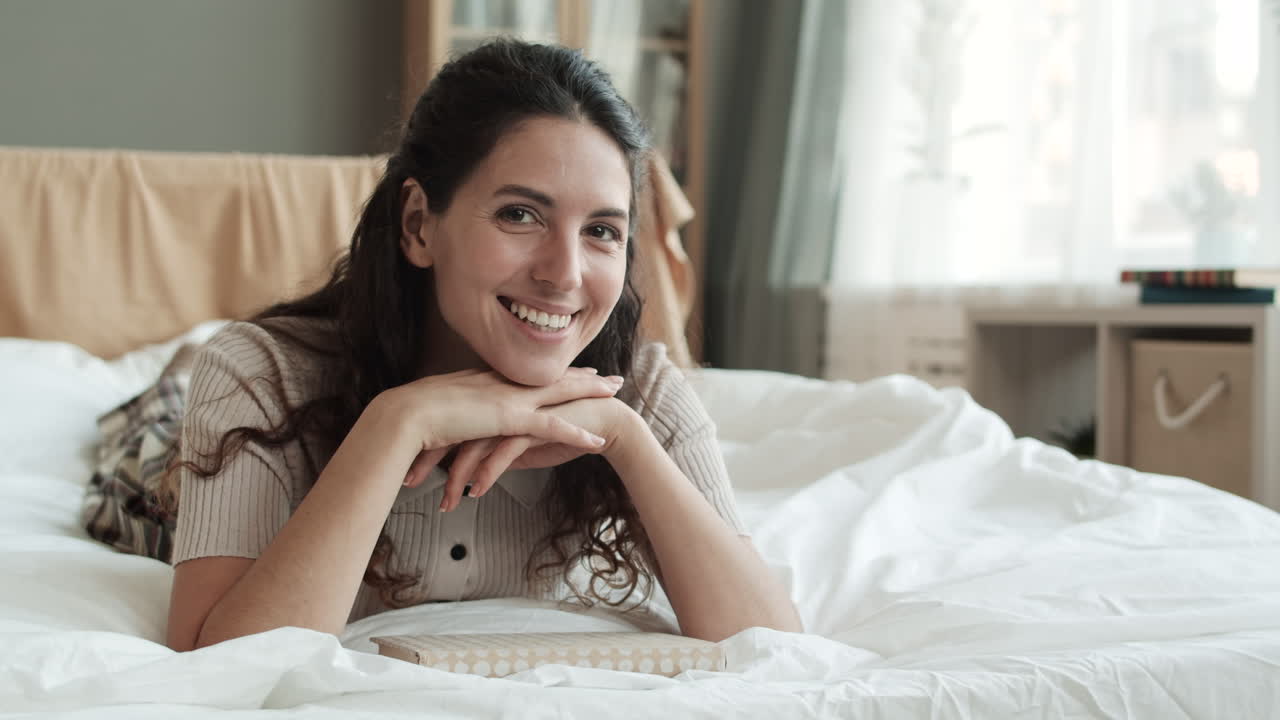 una mujer acostada en la cama sonriendo.