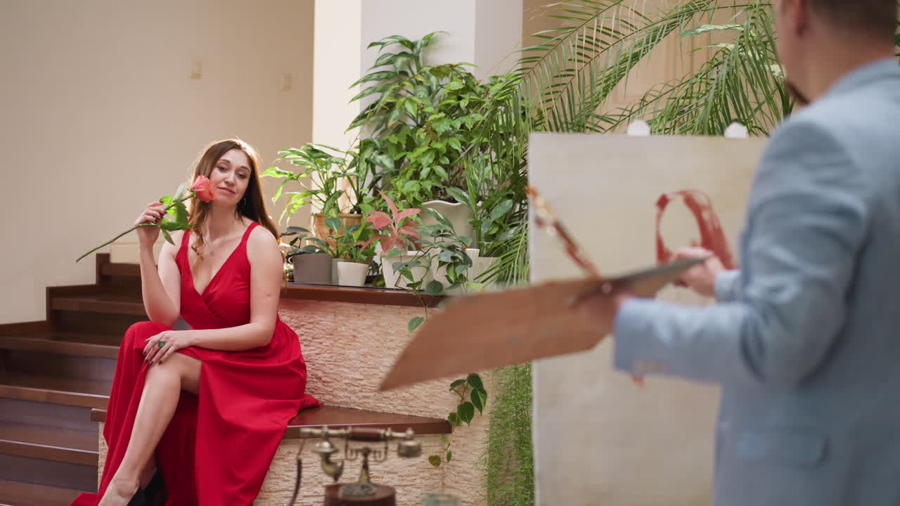 꽃과 예술가와 함께 생활 그림 세션에서 모델. 금발 여자가 디자이너 스튜디오에서 초상화를 위해 매혹적인 포즈에 앉아 있습니다. 매력적인 여성과 화가.