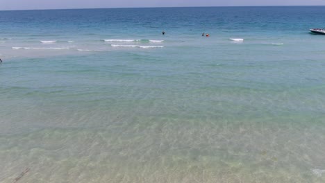 Drone-aerial-view-in-Vietnam-flying-over-Phu-Quoc-island-Sao-beach,-crystal-clear-blue-turquoise-water,-small-waves-and-people-swimming-on-a-sunny-day